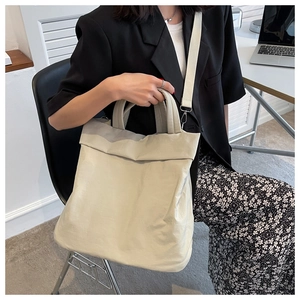 Minimalist beige nylon tote bag shown in a professional office setting with a model