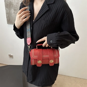Red Boston bag with wide jacquard strap and rivet details shown on a model