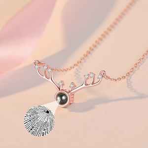 Macro detail of rose gold reindeer antler necklace showing 100 languages projection stone