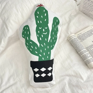 Detailed view of creative cactus shaped decorative pillow on soft white bedding sheets