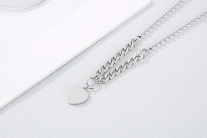 Detailed shot of silver double-strand necklace with Cuban and bead chains and heart pendant