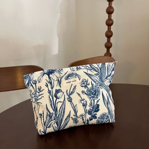 Detailed close-up of a floral canvas cosmetic bag with simple wish label on a wood table