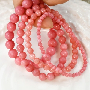Handmade rhodochrosite beaded bracelets for women in five different bead sizes on a white tray