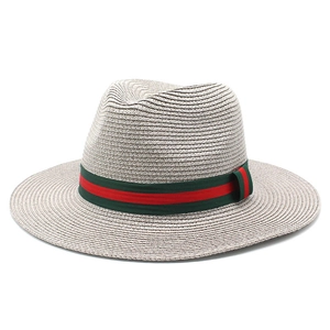 Détail de la texture en paille tressée et du ruban rayé rouge et vert sur le chapeau beige