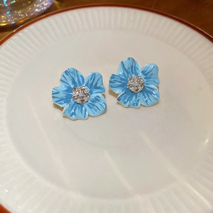 Détail macro de boucles d'oreilles fleurs bleues avec perles et cristaux en plat céramique