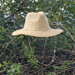Dettaglio cappello di paglia con fascia decorativa in conchiglie e sottogola