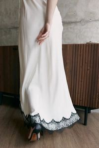 Détail de la robe en satin blanc avec dentelle noire montrant fluidité et texture