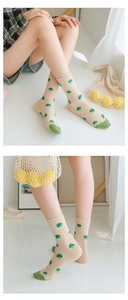 Detailed close-up of beige cotton crew socks featuring green broccoli patterns on a model