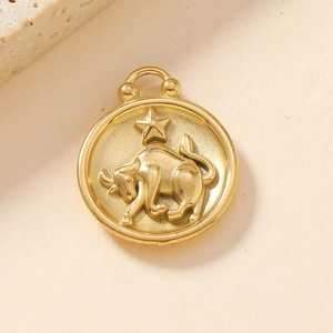 Detailed view of an 18K gold-plated Taurus zodiac pendant on a beige textured surface