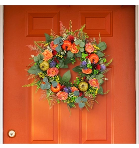 Detail of autumn wreath with orange roses and mini pumpkins on a matching orange door