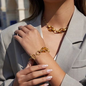 Detail einer Goldkette und eines Armbands mit bernsteinfarbenem Harz und Strass am Model