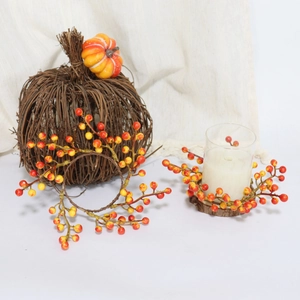 Close-up of orange berry candle ring wreaths with rustic pumpkin decor on white linen