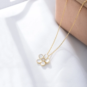 Macro shot of s925 silver gold flower pendant with white enamel petals and zircon