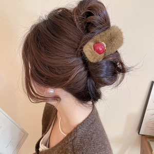 Detail of plush brown faux fur hair claw with a bright red bead shown on a hairstyle