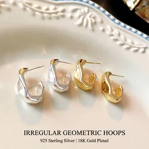Irregular C-shaped earrings with gold and silver plated hammered finish on ceramic plate