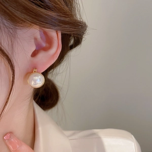 Elegant gold plated pearl huggie hoop earrings for women shown on a fashion model