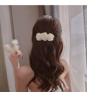 Close-up of elegant white camellia hair clips in satin and organza fabric with beads
