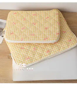 Detail of yellow checkered quilted laptop sleeve with pink floral bow patterns