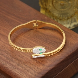 Macro shot of gold snake bracelet head with pavé diamonds and green gemstone eyes