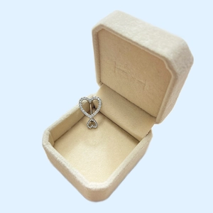 Detailed view of silver heart navel ring with crystals in a beige velvet jewelry box