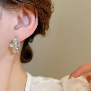 Close-up of irregular zircon geometric silver hoop earring worn by a model in luxury style