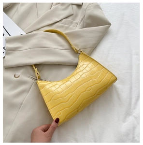 Detail of a bright yellow crocodile pattern underarm bag with a stylish half-moon design