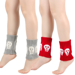 Detail of knitted leg warmers in red and grey with white skull patterns for winter boots