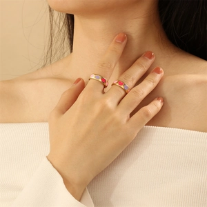 Close-up of gold rings with colorful pink and purple enamel heart details on fingers
