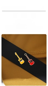 Detail of red and yellow electric guitar enamel pins attached to a brown canvas backpack