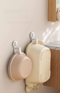 Detail of adjustable spring-loaded washbasin hook on white bathroom tile wall