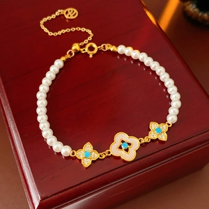 Dettaglio del bracciale di perle placcato oro con ciondoli a quadrifoglio in zircone