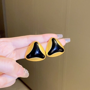 Close-up of vintage gold-trimmed triangle earrings with black enamel inlay