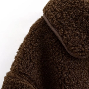 Gros plan sur la texture sherpa marron foncé d'une veste à col montant pour femmes