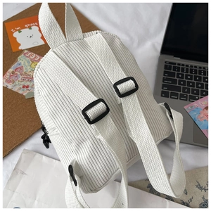 Detail view of white corduroy mini backpack back with adjustable woven straps in lifestyle setting