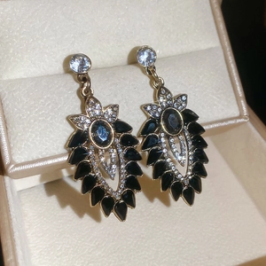 Dettaglio orecchini a fiore vintage con pietre blu e cristalli a goccia neri