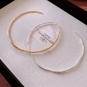 Minimalist gold and silver plated wave pattern open collar necklaces in a tray