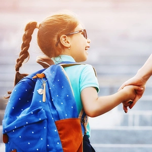 Close-up of a baseball and bat keychain hanging on a blue polka dot backpack in sunlight