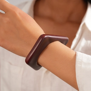 Macro shot of dark reddish-brown resin geometric square bangle on a woman's wrist