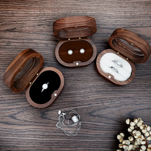 Overhead view of oval walnut wood jewelry boxes with velvet lining on dark wood desk