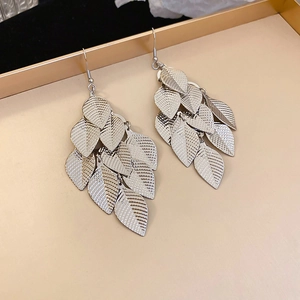 Close-up of silver textured leaf tassels on metallic earrings over a tray