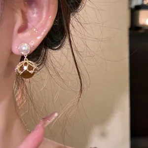 Vintage 18K gold plated pearl earrings with amber resin beads shown on a model