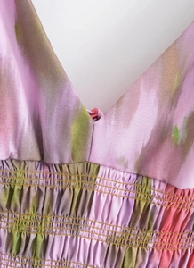 Detail of V-neck tie-dye dress featuring elastic smocking and vibrant floral patterns