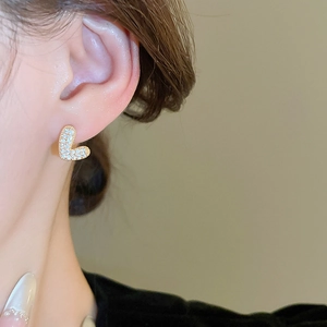 Détail de boucles d'oreilles en L dorées avec micro-pavé de zircons sur un mannequin