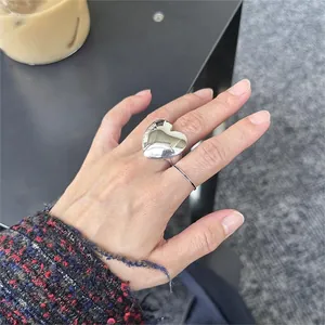 Polished silver heart ring and minimalist band set shown in a lifestyle hand-worn view