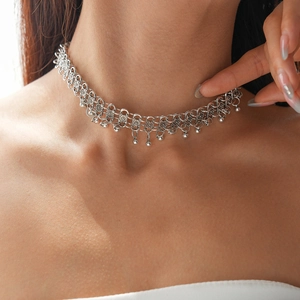 Detail of silver bohemian choker necklace with geometric cutouts and tassel ball charms
