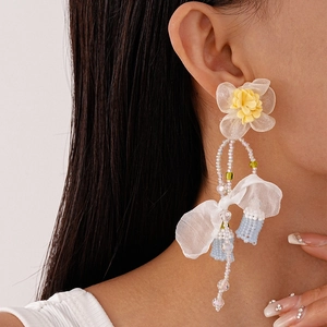 Close-up of handmade floral lace tassel earrings with glass beads and fabric petals