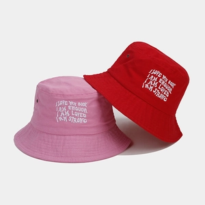 Detail of pink and red canvas bucket hats with white motivational text embroidery
