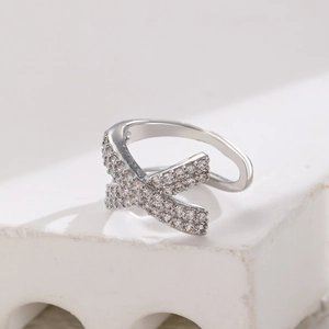 Macro shot of silver X-shaped ear cuff featuring a double cross design with pavé crystals