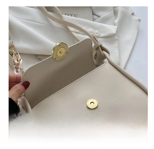 Close-up of cream textured leather bag with gold magnetic buckle and floral scarf detail