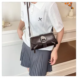 Detail of dark brown leather crossbody bag with silver buckle and side zipper accents